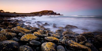 Pebbly shoreline at Crescent Head New South Wales Australia with gentle waves washing over stones fine art print