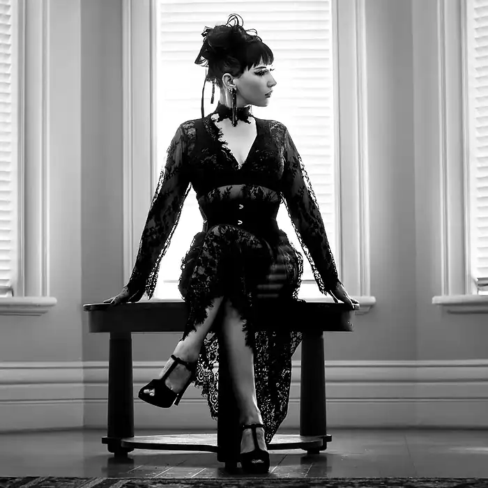 Monochrome fashion portrait of a woman sitting in front of a window in silhouette