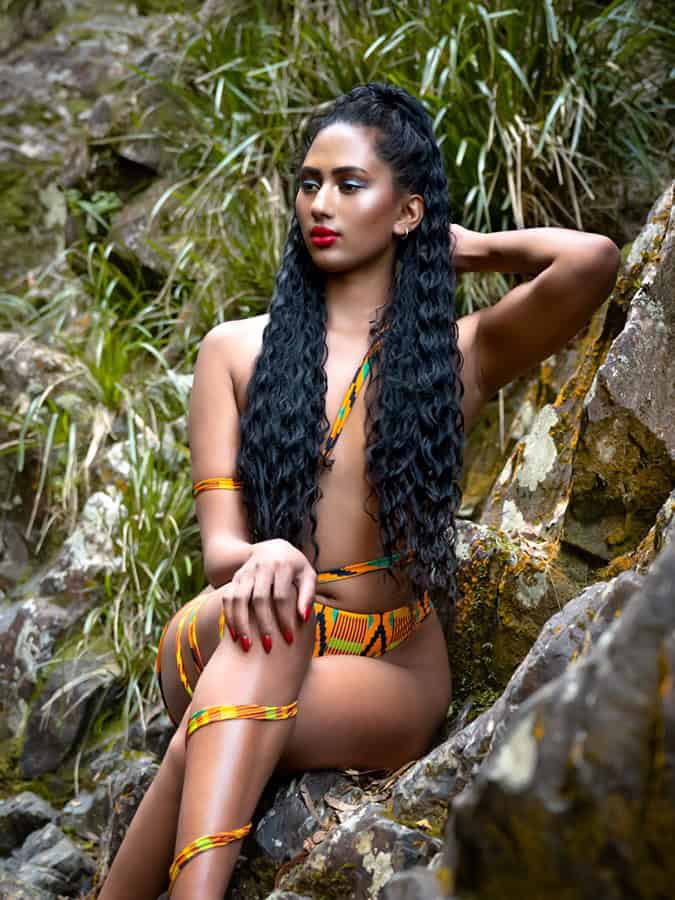 Glamour portrait of a woman with long black hair in front of a waterfall