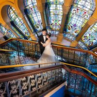 Married couple having photos taken in front of a stained glass window at Queen Victoria Building, Sydney