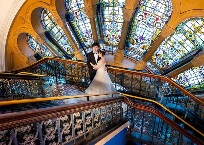 Married couple having photos taken in front of a stained glass window at Queen Victoria Building, Sydney