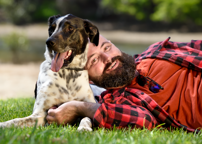 Man lying on the ground next to his dog, smiling