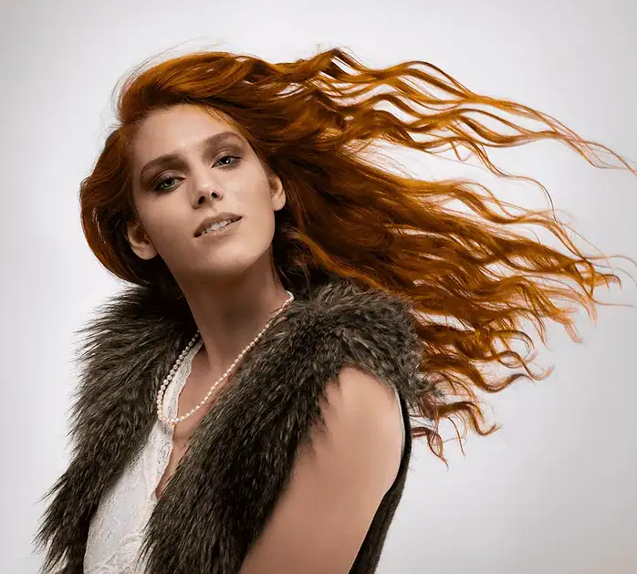 Studio portrait of a woman with flowing red hair captured in an elegant editorial style