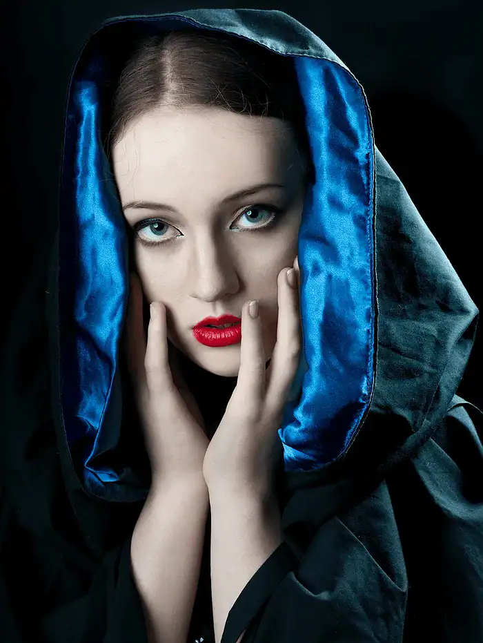 Pensive portrait of a woman looking into the camera wrapped in a black glossy shawl