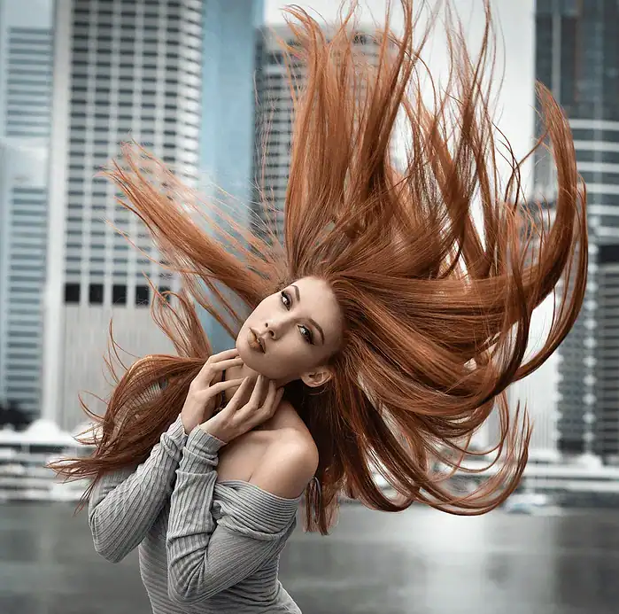 Portrait of a woman flicking her hair in front of an urban cityscape backdrop