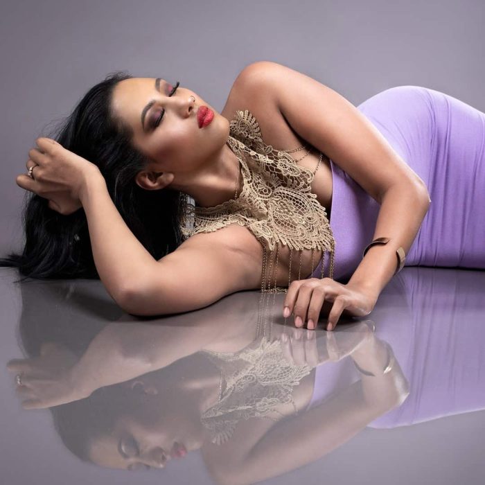 Studio portrait of a lady elegantly posed on a reflective floor