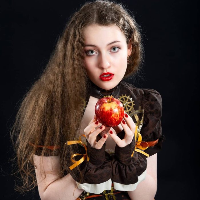 Girl holding an apple on the poster cover for the musical "Snow White Take a Bite"