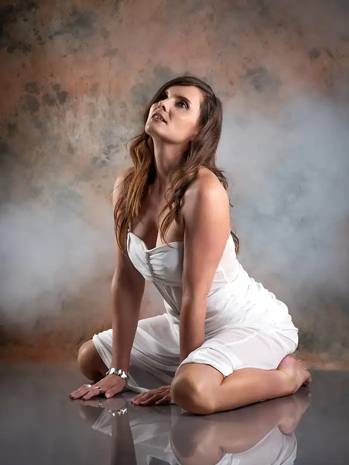 Studio portrait of a woman posing on the floor with a dramatic smoke background