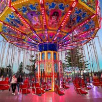 Colourful merry-go-round ride at Coffs Harbour Jetty Beach, vibrant carnival scene, lifestyle photography