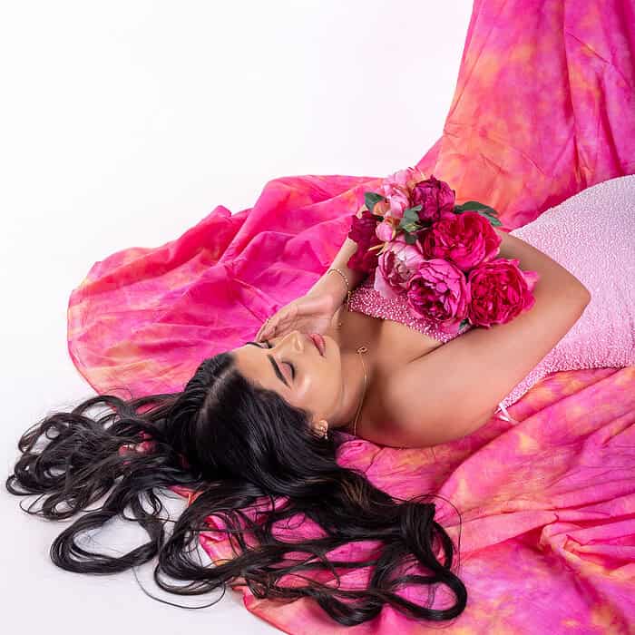 Studio portrait of girl lying on floor with pink flowers, hair spread out, creative lifestyle photography