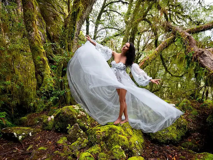 Fashion portrait of a woman wearing a flowing white ethereal dress in a rainforest setting