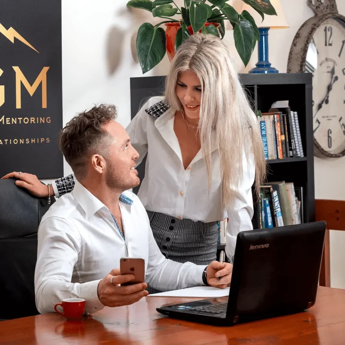 Business professional in an office setting with team member working in the background