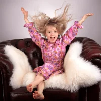 Daughter sitting on a leather lounge happily throwing her hands in the air