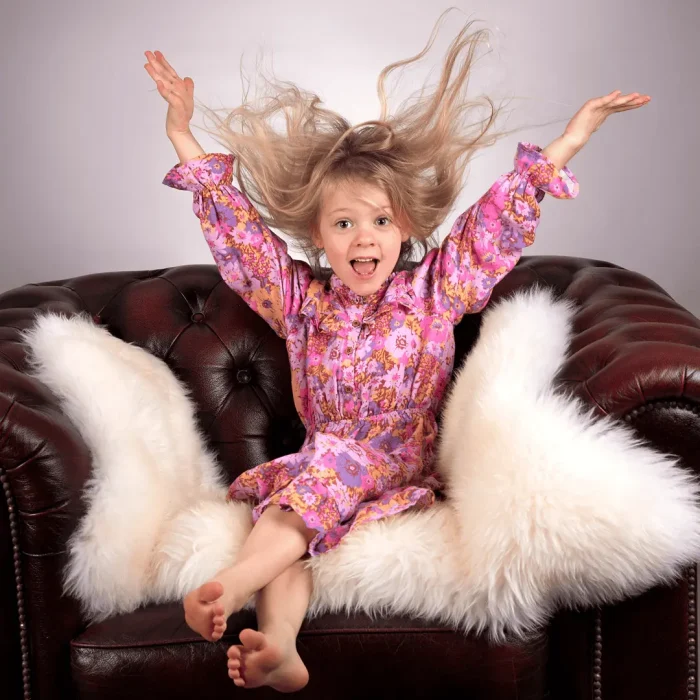 Daughter sitting on a leather lounge happily throwing her hands in the air