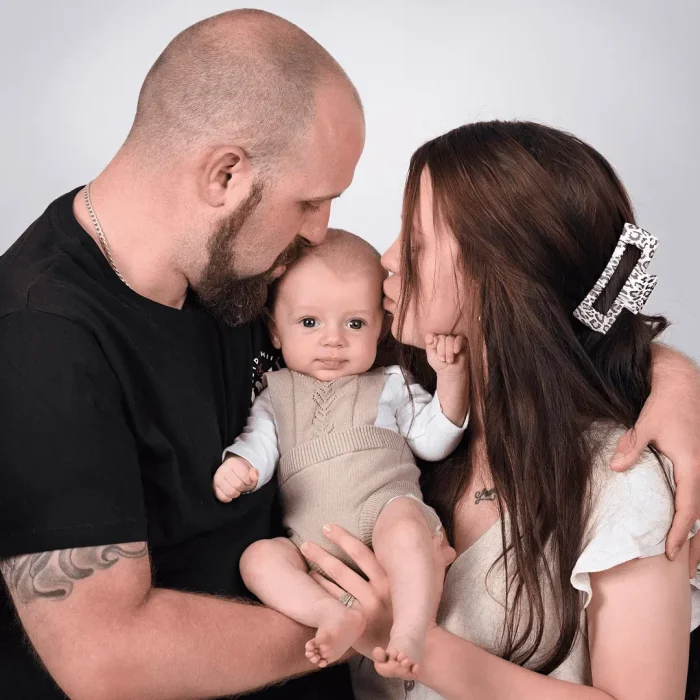 Happy couple kissing their newborn baby