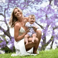 Mother and baby smiling with blooming jacarandas in the background
