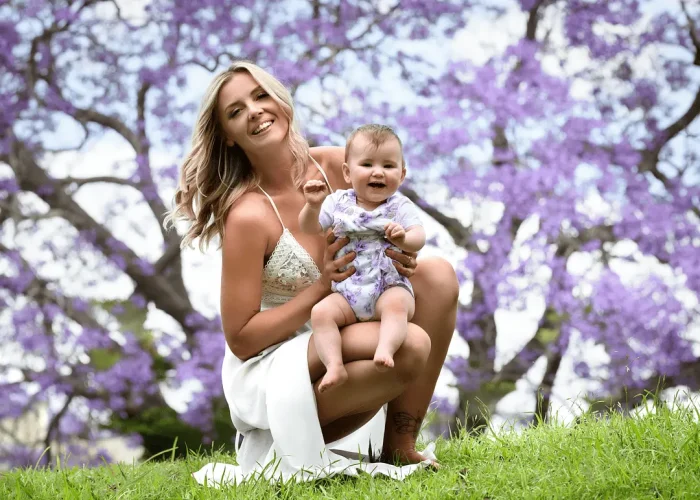 Mother and baby smiling with blooming jacarandas in the background