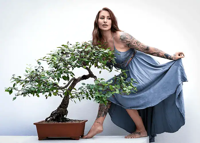 Fashion portrait of a woman posing with a large bonsai plant