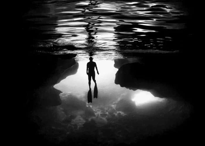 Silhouette of a diver at the entrance of an underwater cave