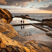 Two people silhouetted at Bermagui Blue Pools during sunrise