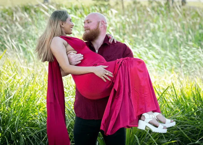 Husband playfully carrying his pregnant wife outdoors