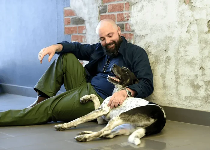 Man sitting on the ground next to his dog, smiling