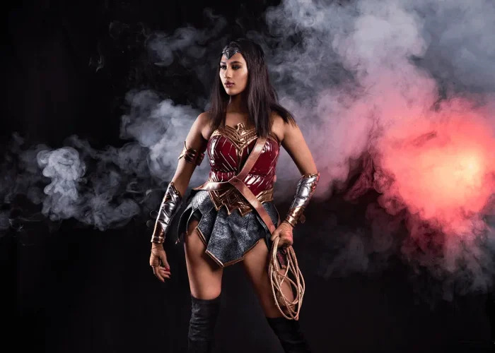 Studio portrait of a lady dressed as Wonder Woman with smoke and reflective floor in a unique pose