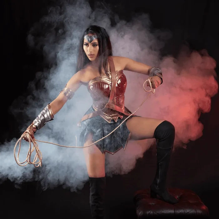 Studio portrait of a lady dressed as Wonder Woman with smoke and reflective floor in a different pose