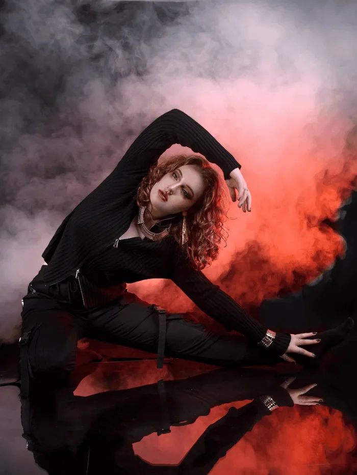 Studio portrait of a lady in cool clothing with smoky background and red lighting