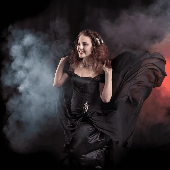 Studio portrait of a lady in a formal black dress flowing with smoke in the background