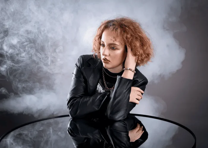 Studio portrait of a lady leaning on a mirror with a smoky background
