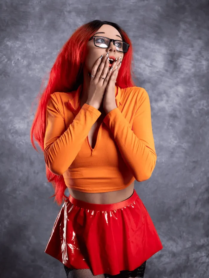 Studio cosplay portrait of a lady with red hair in an orange outfit