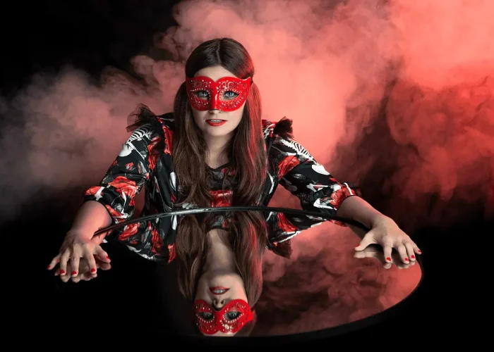 Studio portrait of a model with a red mask and smoky background reflected in a mirror