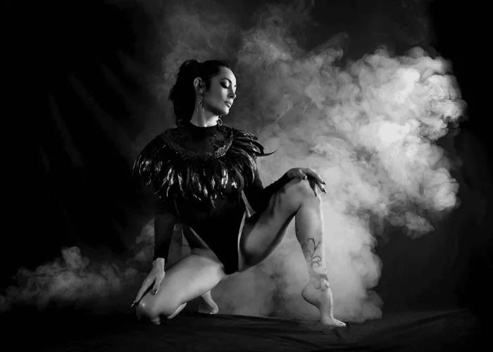Studio black-and-white portrait of a girl in a black outfit with a smoky background